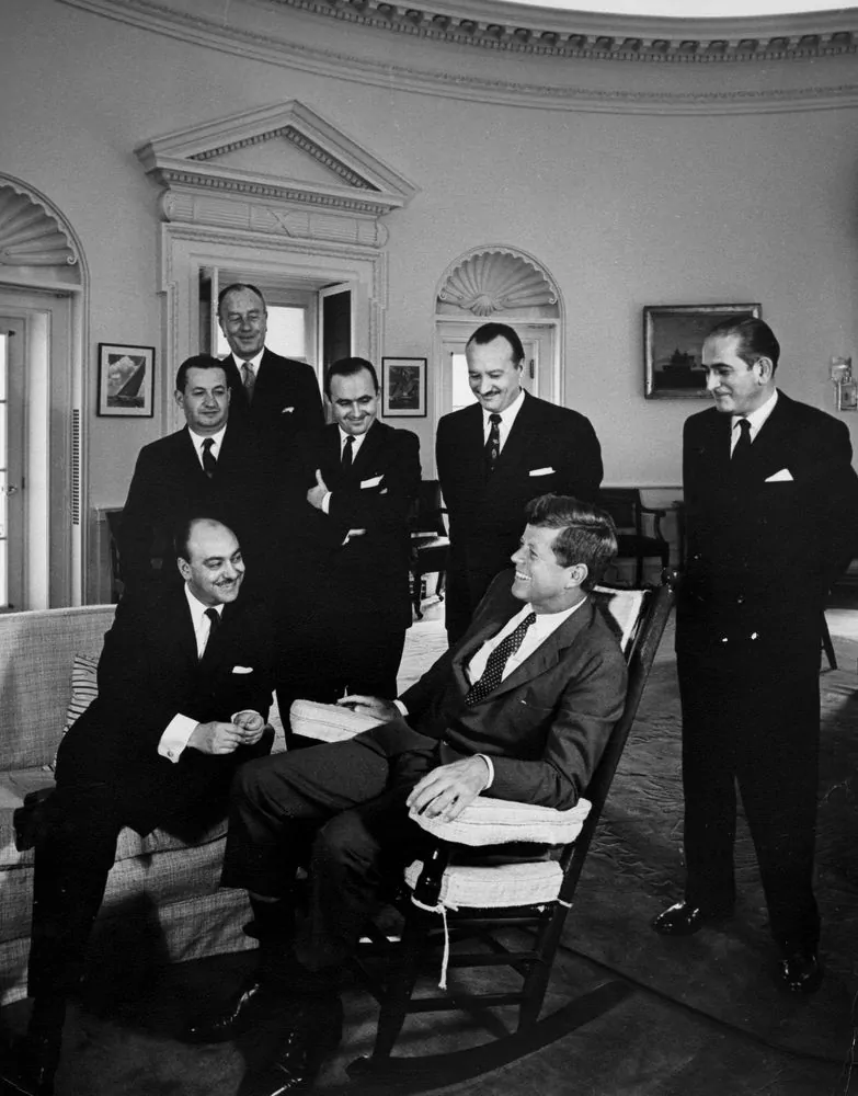 President John F. Kennedy meets with Carlos Martínez Sotomayor, Foreign Minister of Chile. Carlos Martínez Sotomayor (seated on couch); President Kennedy (in rocking chair); Walter Müller, Ambassador of Chile (at back); others unidentified. Oval Office, White House, Washington, D.C.