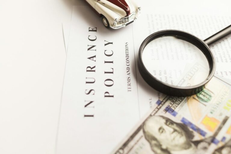 vlad-deep-mCqi3MljC4E-unsplash Will Insurance Companies Accept Online Valuations? Image shows an insurance policy under a magnifying glass, a toy car and $100 bill.