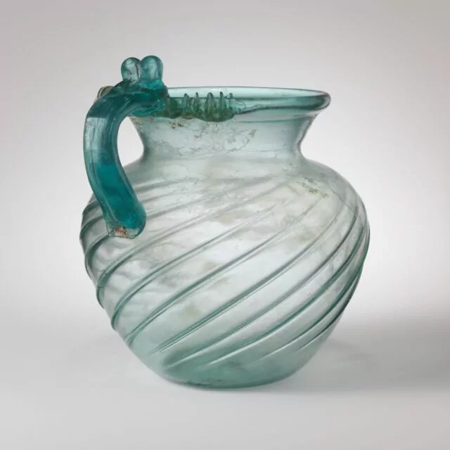 Title: Glass jugPeriod: Early to Mid ImperialDate: late 1st–2nd century CECulture: RomanMedium: Glass; blown in a dip mould and tooledDimensions: Height: 7 15/16 in. (20.2 cm)
