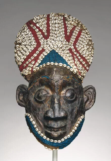 Helmet crest from a nja masquerade, wood, copper, glass beads, raffia palm, and cowrie shells, Bamum kingdom, Cameroon, 19th century.