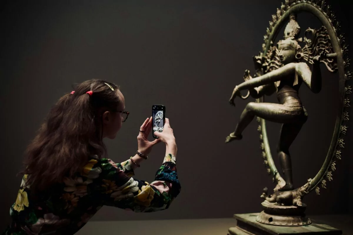 Woman photographing an antique bronze Shiva for antique valuation - Photo by Huseyin Akuzum on Unsplash